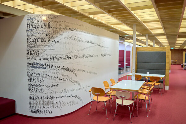 Schwarze Schriftzeichen auf einer Wand neben einem Tisch für die Gruppenarbeit
